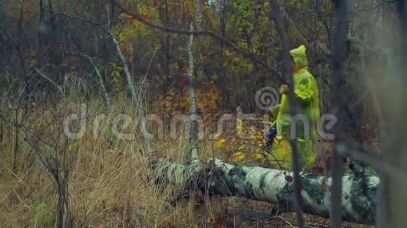 一个穿着雨衣的女人走过森林踏过一棵倒下的树视频的预览图