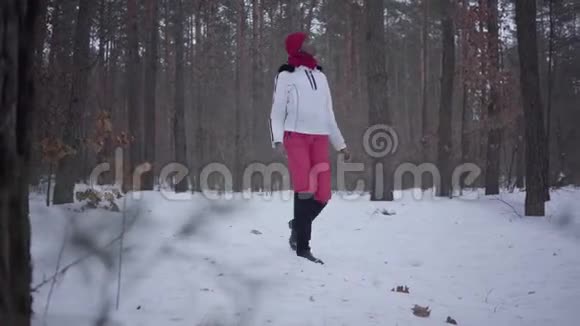 在冬季森林里散步的非裔美国女孩穿着白色保暖夹克的漂亮女孩独自度过时光概念视频的预览图