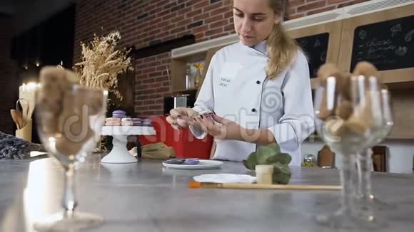 年轻的女厨师用奶油把两半马卡龙连接起来视频的预览图