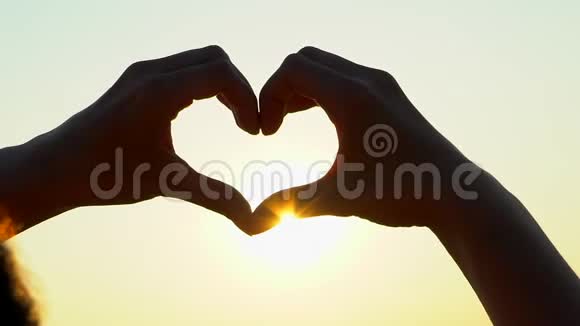 日落的心手女人用双手在日出或日落时塑造心灵在大自然的夏天男性心脏视频的预览图