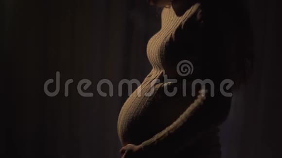 孕妇的手在黑暗的房间里温柔地抚摸着她的腹部女士在等孩子视频的预览图