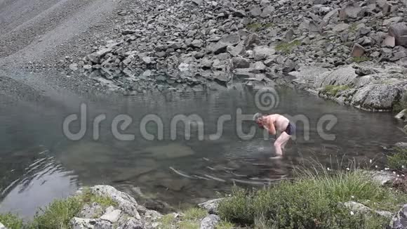 脱衣男子在湖中洗脸湖中山神阿尔泰山脉视频的预览图