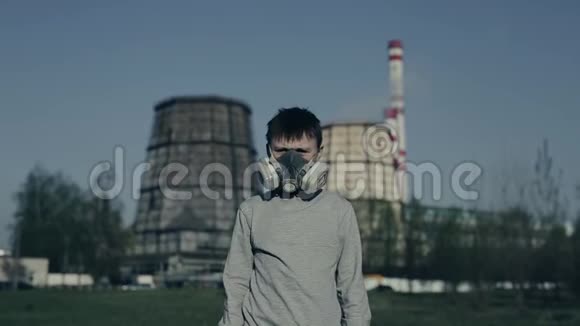 十几岁的年轻人戴着防毒面具对着工厂的烟囱这个男孩因为污染而窒息他咳嗽视频的预览图