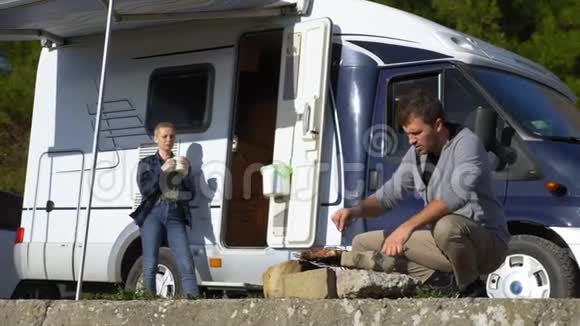 一个男人在户外的烤架上做肉背景是汽车旅馆视频的预览图