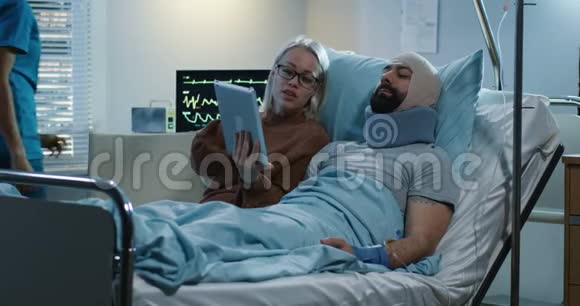 女人用平板电脑展示受伤男人视频的预览图