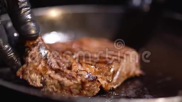 手里拿着黑色的食物手套把一块肉放在另一边的锅上紧紧地贴在一起视频的预览图