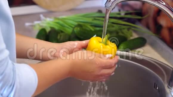 女人在厨房里洗黄胡椒自制食品概念慢动作视频的预览图
