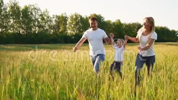 幸福的家庭父亲母亲和儿子穿着白色t恤在田野里奔跑视频的预览图