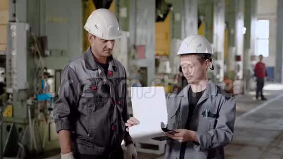 一名工厂工人和船员的肖像谈论工作过程持有文件视频的预览图