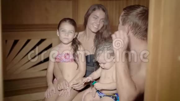 带着戴帽子的孩子的幸福家庭在桑拿浴中放松视频的预览图