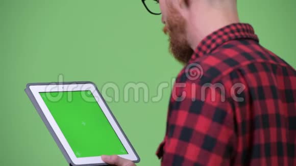 用数字平板电脑观看留着胡子的戴着可怕锁的时髦男士的背影视频的预览图