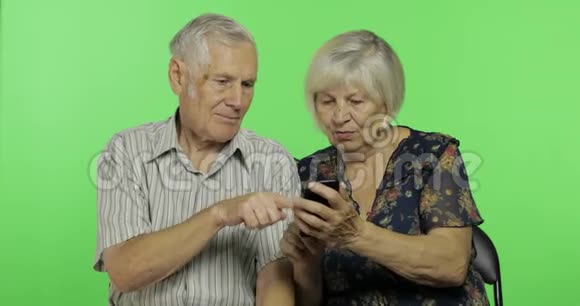 年长的男人和女人坐在一起在智能手机上工作铬键视频的预览图