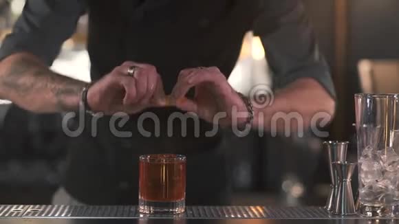 面目全非的酒保用鸡尾酒把橘子皮挤到杯子里然后把剩下的放进杯子里视频的预览图