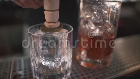 不可辨认的酒保在现代酒吧里用破冰器在玻璃上刺冰来喝酒关门视频的预览图