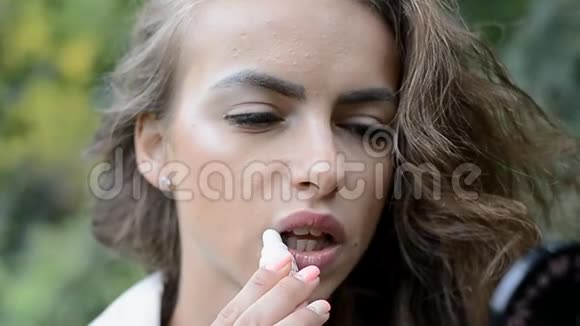 一位用口红涂嘴唇的漂亮女孩的肖像视频的预览图