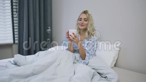 可爱的女人在床上喝酒视频的预览图