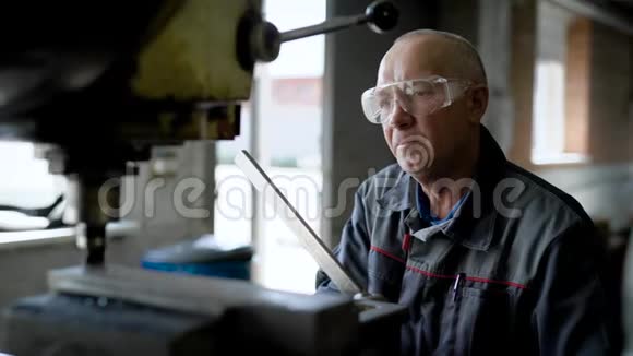 特写镜头一位老的专业的工厂工人在站立的钻机上加油视频的预览图
