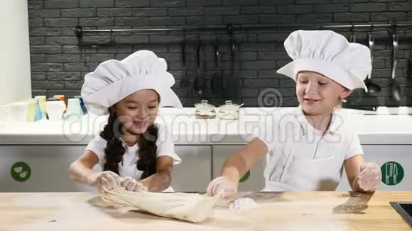假装成人两个戴着厨师帽和围裙的孩子玩着dook滚动和触摸它共同烹饪理念视频的预览图