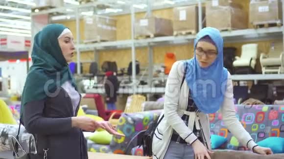 两个年轻的穆斯林妇女在家具店里选择沙发视频的预览图