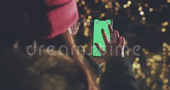 女孩正在使用智能手机与绿色屏幕的肖像模式在晚上休闲生活方式视频的预览图