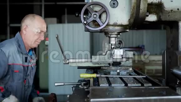 老有经验的工厂工人在特殊的机器上穿着保护制服钻一块金属视频的预览图