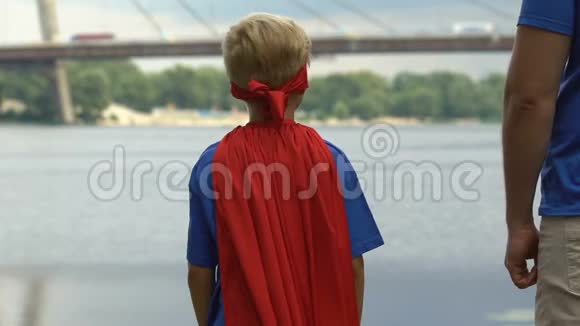 穿着超级英雄服装的不安全男孩得到父亲的支持牵着手视频的预览图