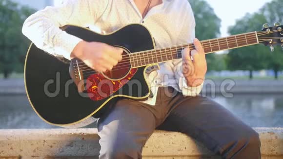 人坐在公园里的石砌木板路上弹吉他近距离射击视频的预览图