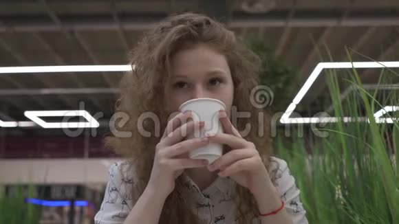 年轻漂亮的红发女人坐在咖啡馆里用棉花糖喝咖啡视频的预览图