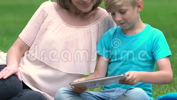 怀孕的妈妈和儿子玩平板电脑游戏快乐的母亲计划生育视频的预览图