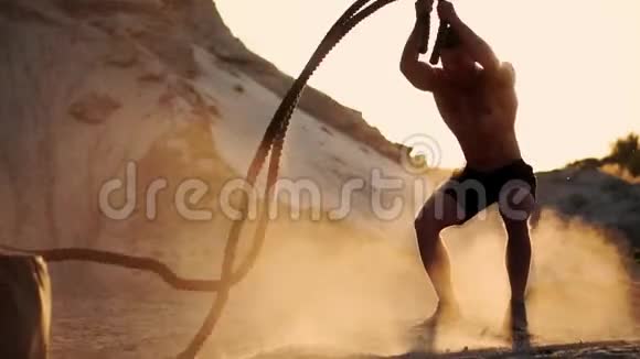 男运动员在沙滩上做推UPS在地上打绳子在沙滩上做循环训练视频的预览图