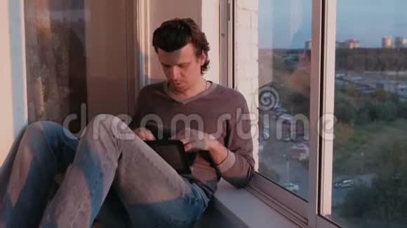 疲惫的男人在笔记本电脑上工作晚上日落时坐在阳台上睡着了视频的预览图