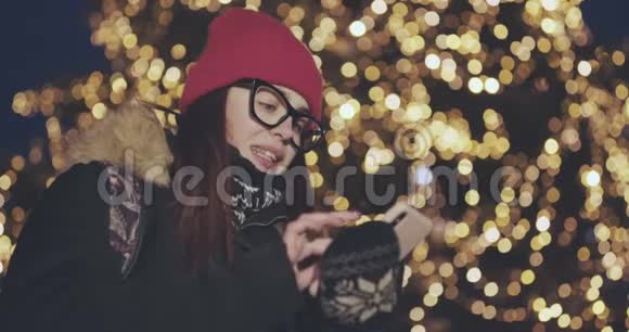 年轻女子在拥挤的街道上使用智能手机她正在检查邮件聊天或新闻夜晚的城市视频的预览图