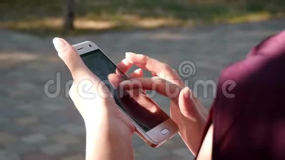 在夏季公园的背景下女性手中的智能手机特写女人手指触摸屏幕视频的预览图
