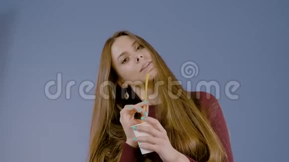 一个美丽模特的肖像带着可爱的微笑拿着一个纸杯喝鸡尾酒视频的预览图