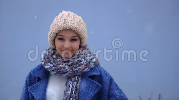 一个微笑的女人在冬天的背景下竖起大拇指的肖像冬季概念雪和女人视频的预览图