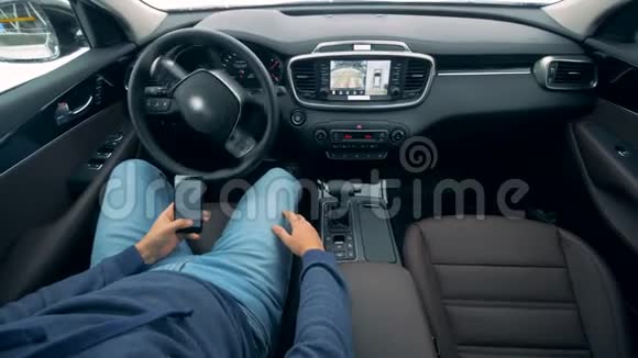 当司机浏览他的手机时汽车正在自动移动未来派自动停车场视频的预览图