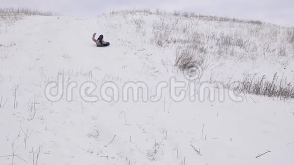 在冬季公园的圣诞假期里孩子们从大雪山滑过雪橇慢动作视频的预览图