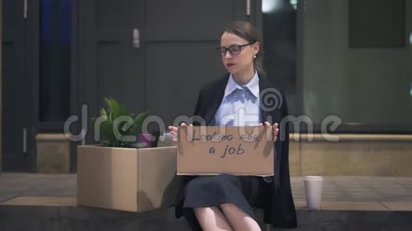 可怜的女人坐在一张硬纸板上在街上找工作视频的预览图