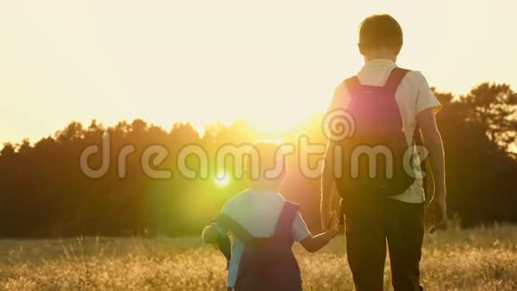 一个游客的两个兄弟背着背包走着在日落时慢动作地抓住背景快乐的孩子视频的预览图