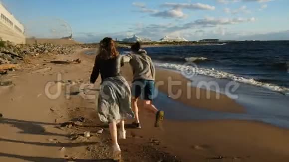 可爱的一对在日落时奔向大海欧洲男女夫妇在海滩上互相玩耍视频的预览图