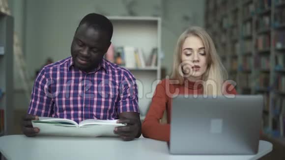 带着笔记本电脑的疲惫女孩和她的非裔美国朋友在看书视频的预览图