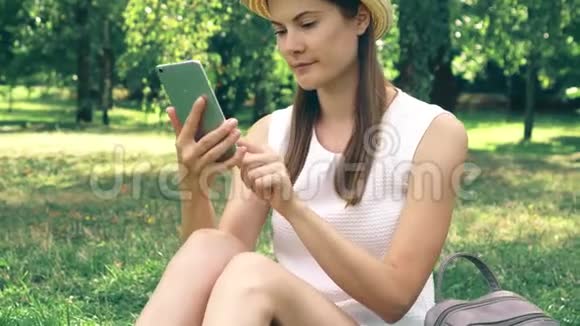 大学生校园里坐在草地上通过手机上的在线应用程序进行视频聊天视频的预览图