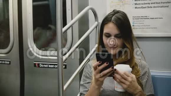 快乐轻松迷人的千禧女孩坐在地铁列车上在线观看智能手机应用程序上的视频微笑视频的预览图