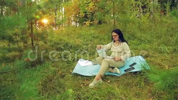 一个戴眼镜的女人正在林间空地上打字视频的预览图