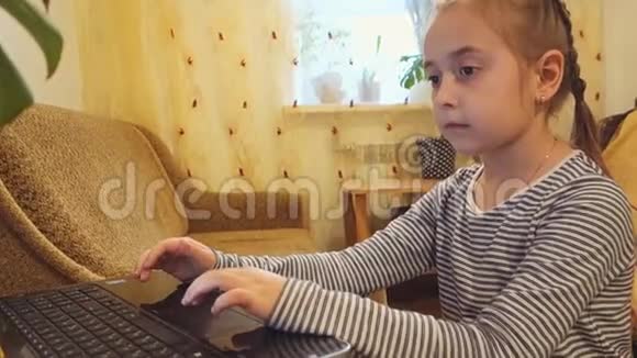 一个小女孩用笔记本电脑工作或玩它视频的预览图