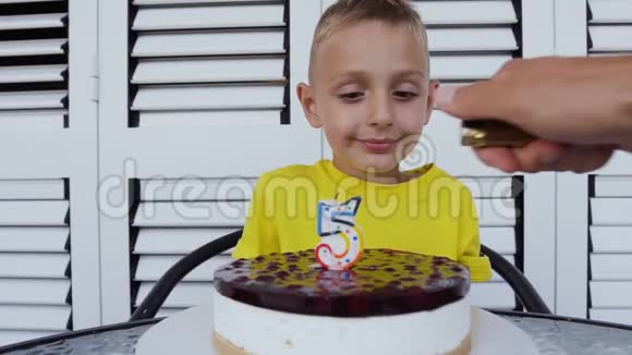 可爱的小男孩正高兴地在他的生日蛋糕上吹蜡烛快乐的小男孩许愿吹蜡烛视频的预览图