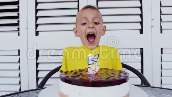 可爱的五岁男孩坐在桌子上庆祝他的生日在白色背景上吹蜡烛特写视频的预览图