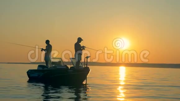 两名渔民在日出时站在船上捕鱼视频的预览图