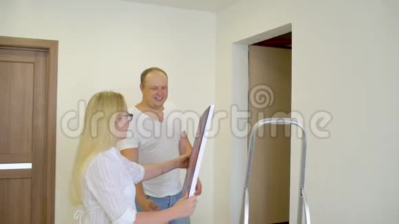幸福夫妇在家墙上挂着照片人男人女人丈夫妻子夫妇家庭装修视频的预览图