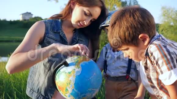带着地球仪向坐在草地上的孩子们展示世界视频的预览图